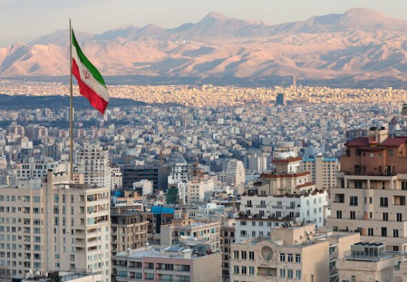 Waving,Iran,Flag,Above,Skyline,Of,Tehran,At,Sunset.